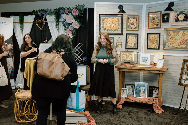 Visitors browsing a booth decorated with framed florals