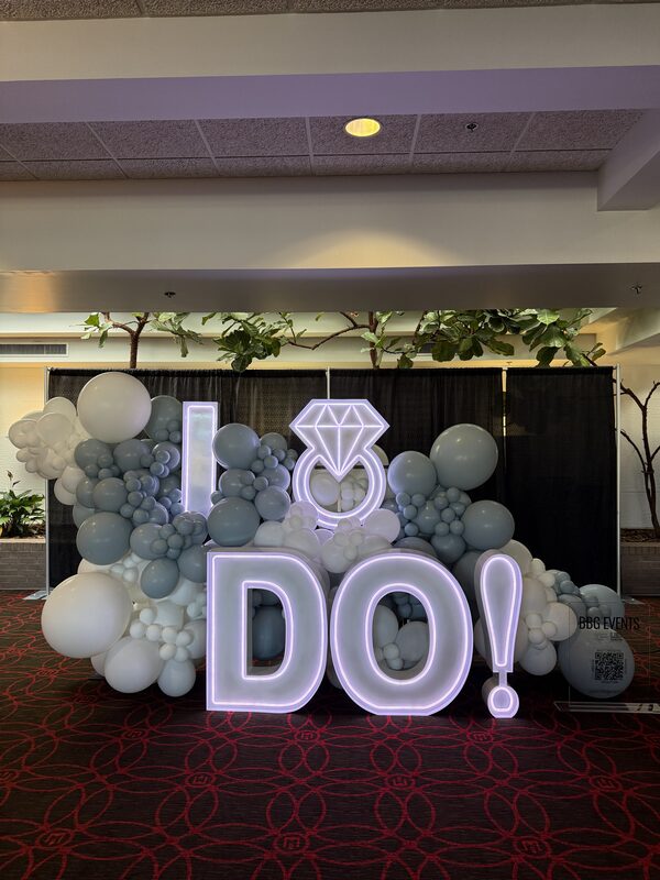 A lit-up I DO sign surrounded by blue and white balloons at the expo