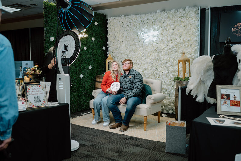 A couple sitting on a sofa at a photo booth display